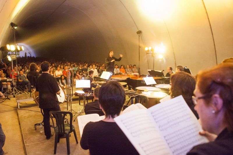 Concert coral dins del túnel de l'autovia A-2 a Vergós, amb els cantaires en primer terme seguint les partitures, el director al centre i el públic assegut al fons