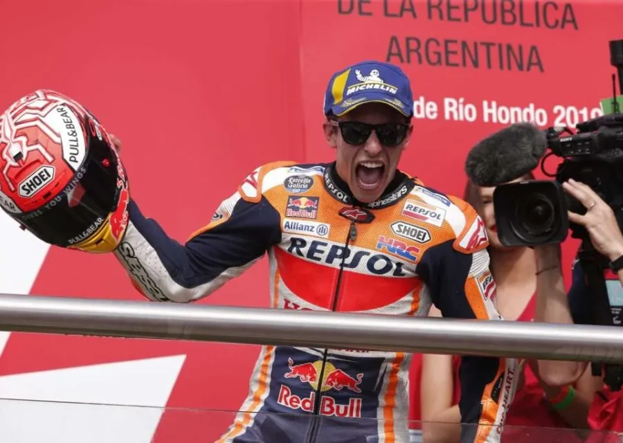 Marc Márquez celebra la victòria al podi del Gran Premi de l'Argentina amb l'equipació de Repsol Honda, alçant el casc amb el braç i cridant, mentre un càmera l'enfoca