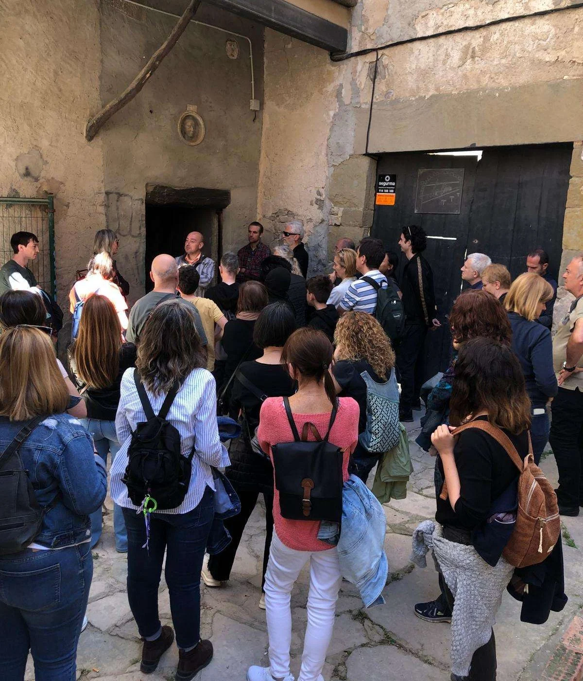 Grup de visitants d'una visita guiada escoltant l'explicació en un pati interior de pedra del nucli antic de Cervera