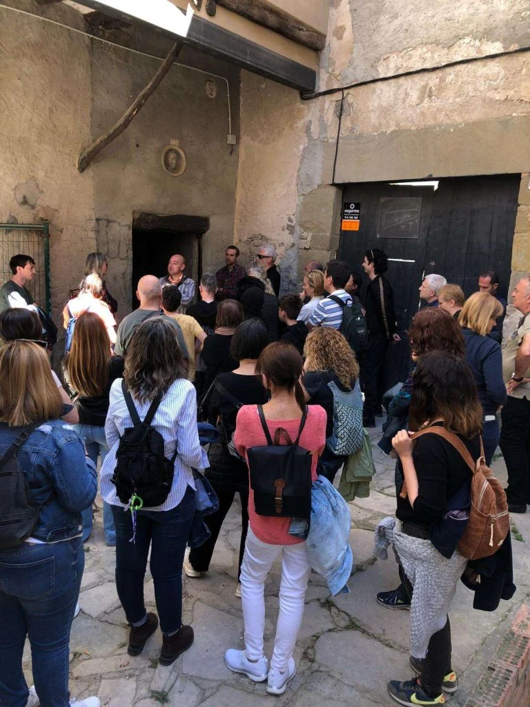 Grup de visitants d'una visita guiada escoltant l'explicació en un pati interior de pedra del nucli antic de Cervera