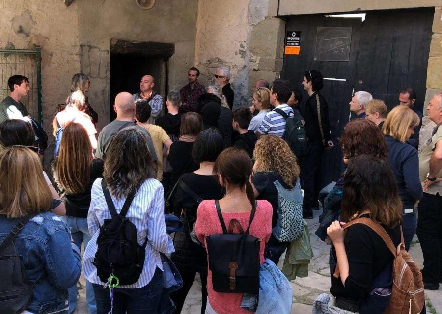 Grup de visitants d'una visita guiada escoltant l'explicació en un pati interior de pedra del nucli antic de Cervera