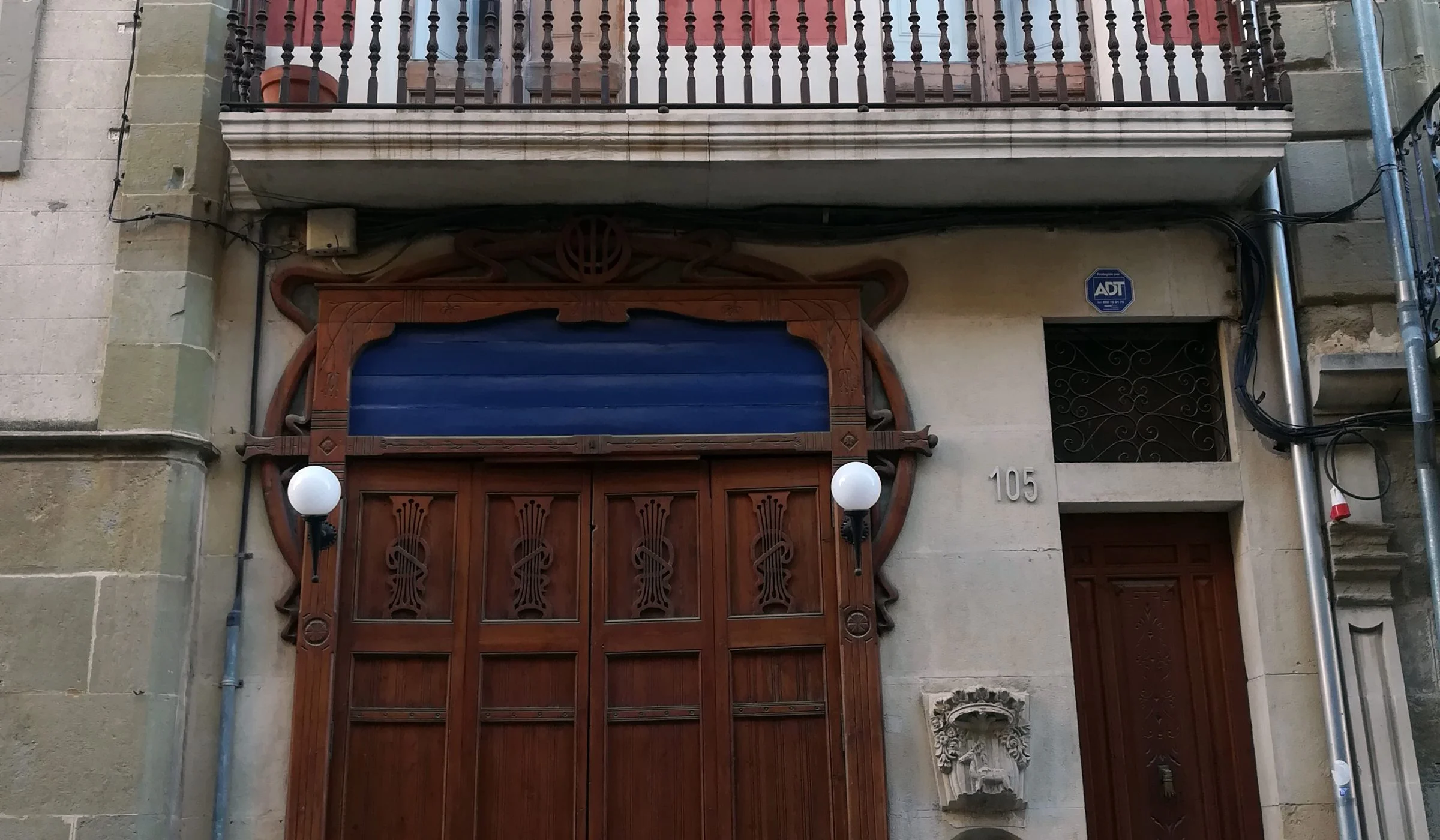 Façana de Cal Greoles amb la porta de la barberia i la font de Sant Agustí.