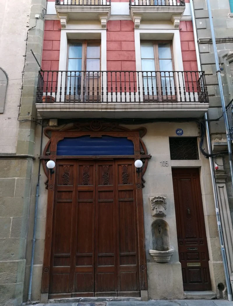 Façana de Cal Greoles amb la porta de la barberia i la font de Sant Agustí.
