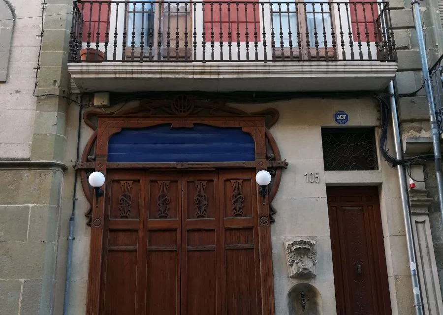 Façana de Cal Greoles amb la porta de la barberia i la font de Sant Agustí.