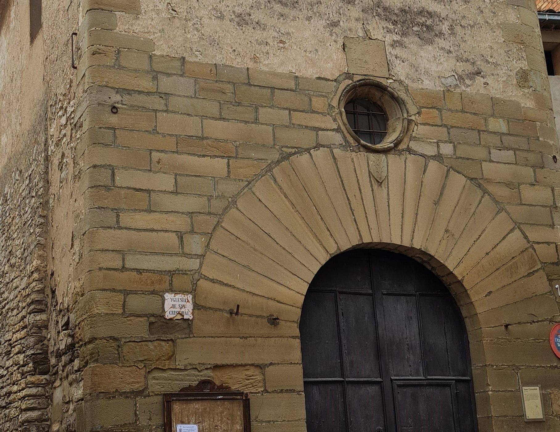 Portal de pedra i campanar de la capella de Sant Cristòfol de Cervera.