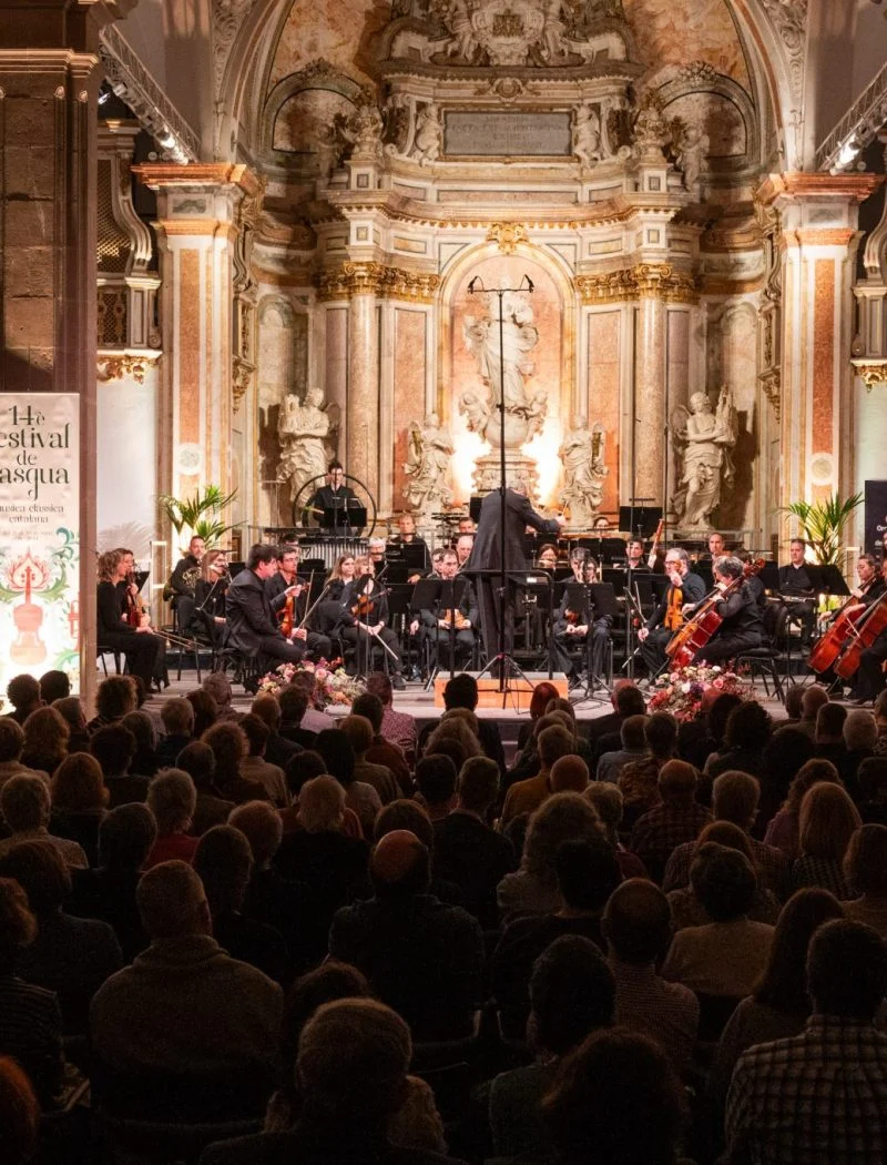 Orquestra i públic al concert inaugural del Festival de Pasqua de 2024, a l’interior d’una església amb retaule barroc.