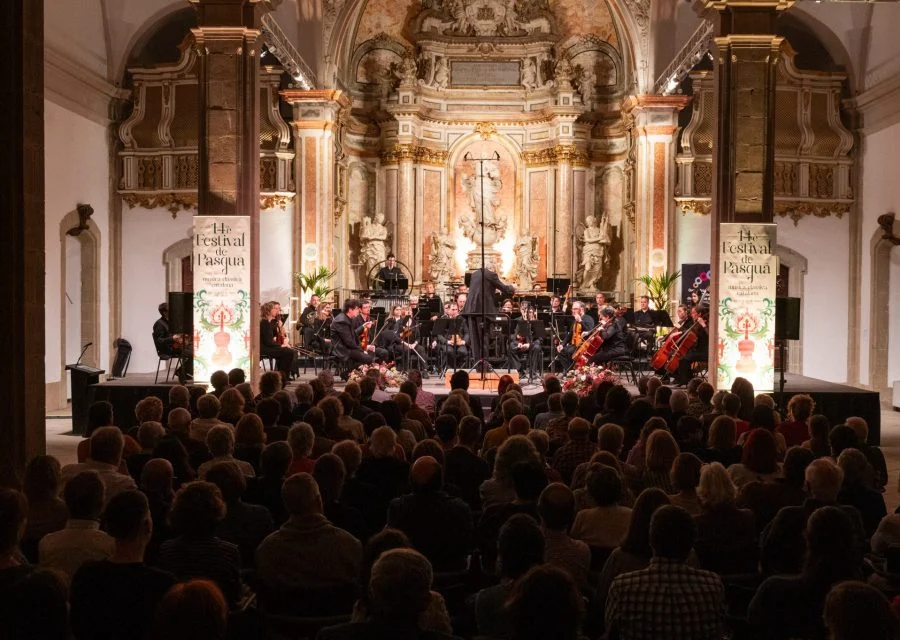 Orquestra i públic al concert inaugural del Festival de Pasqua de 2024, a l’interior d’una església amb retaule barroc.